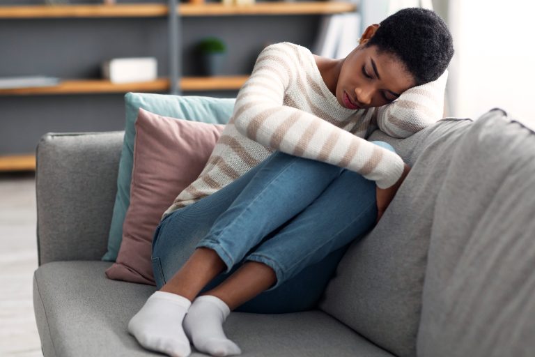 a woman sitting on a couch sadly