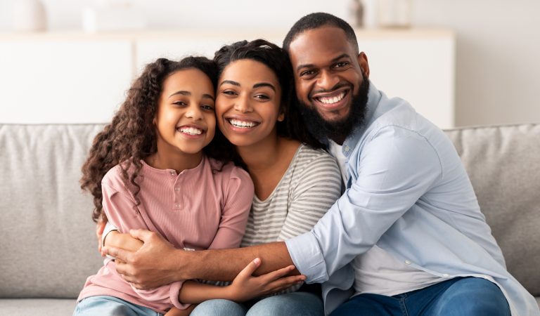 parents and their daughter sitting on the couch smiling